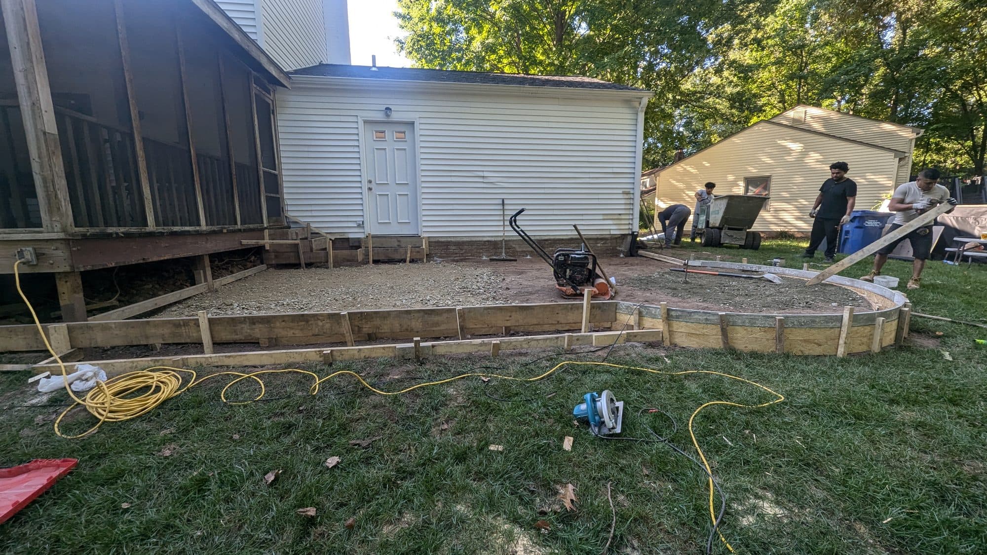 Excavated base with curved wood forms staked out for a circular concrete patio