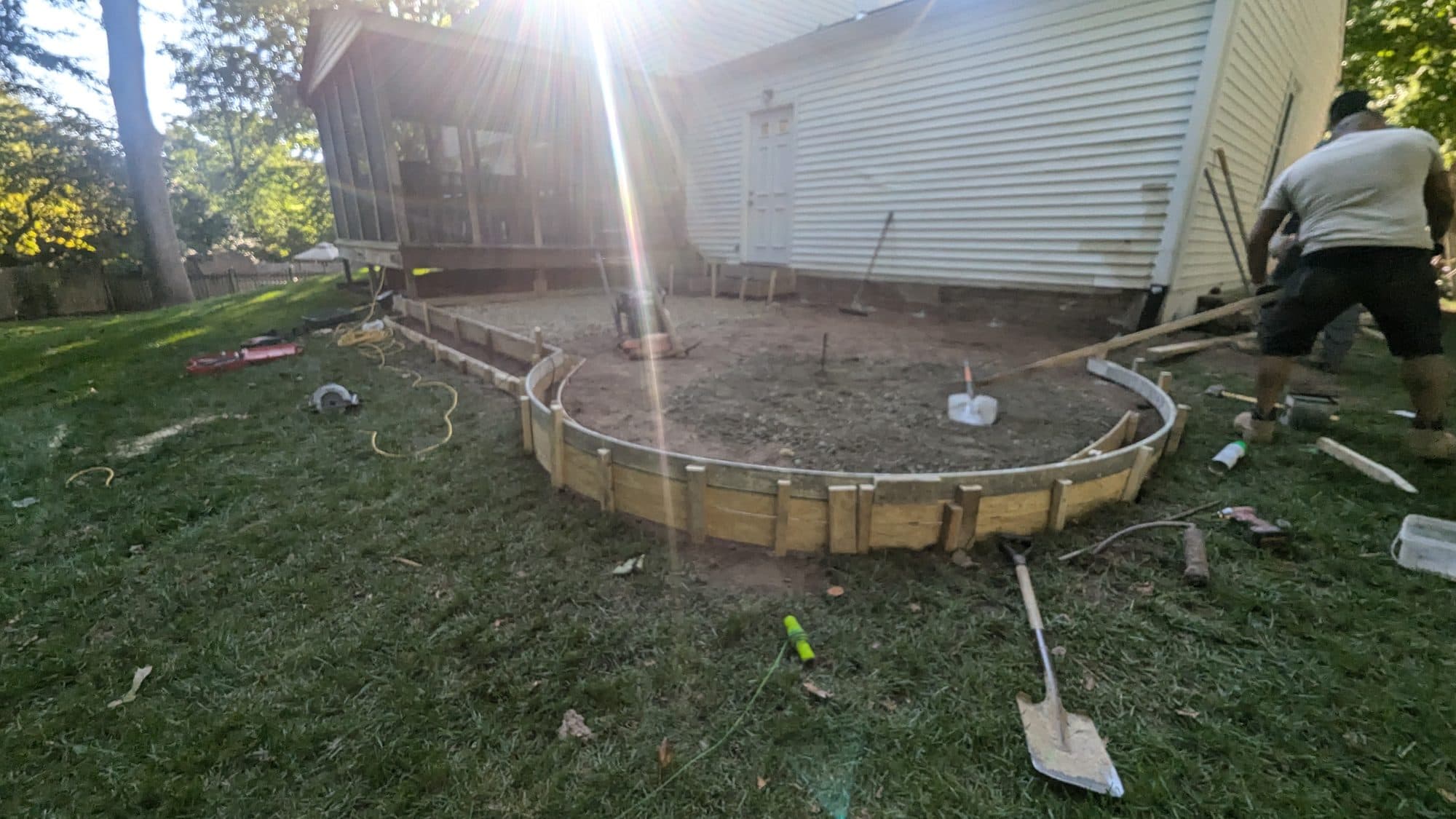 Curved wood forms and gravel base prepared for a circular concrete patio pour