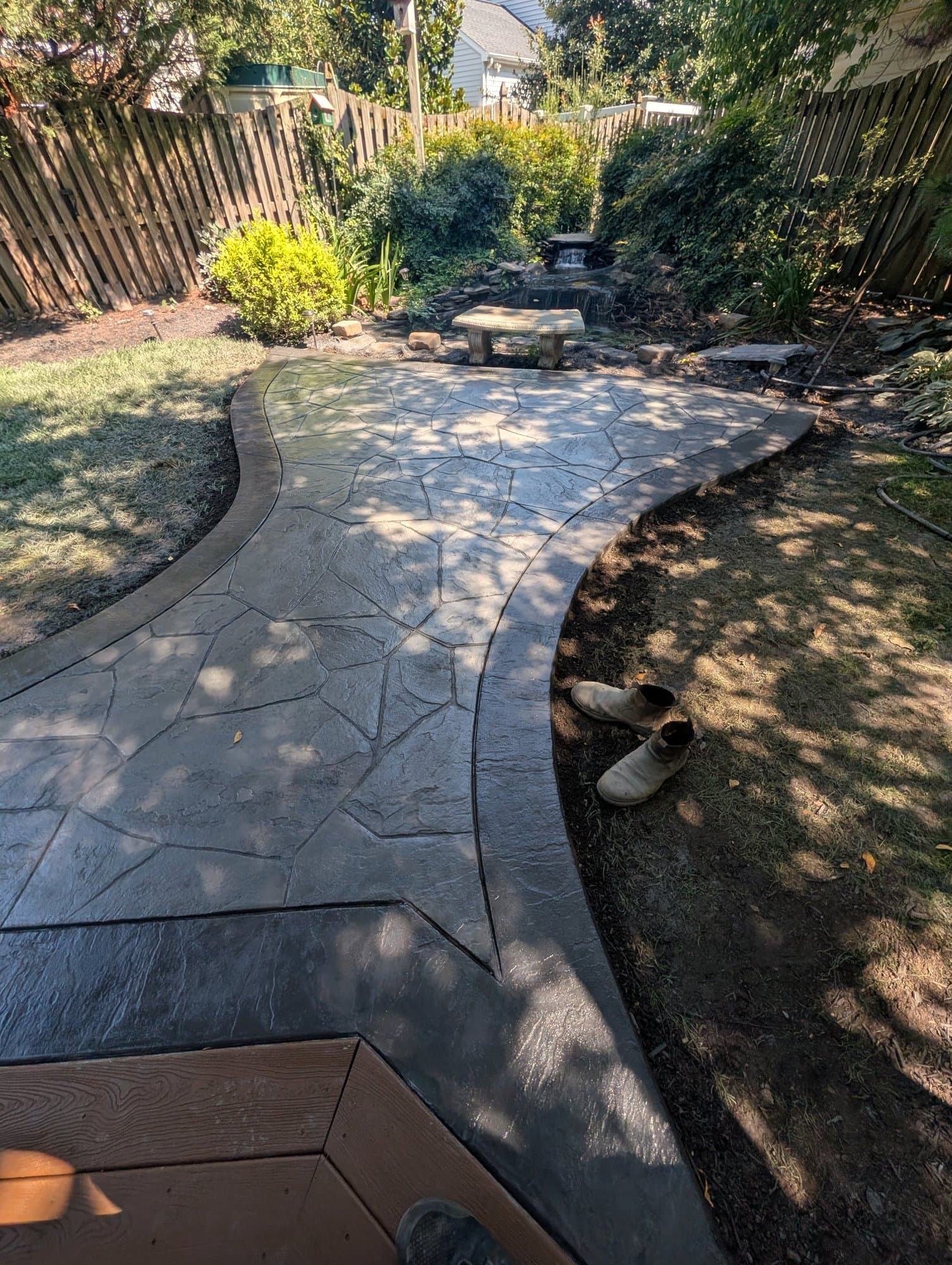 Winding stamped concrete walkway connecting a circular patio to the rest of the backyard