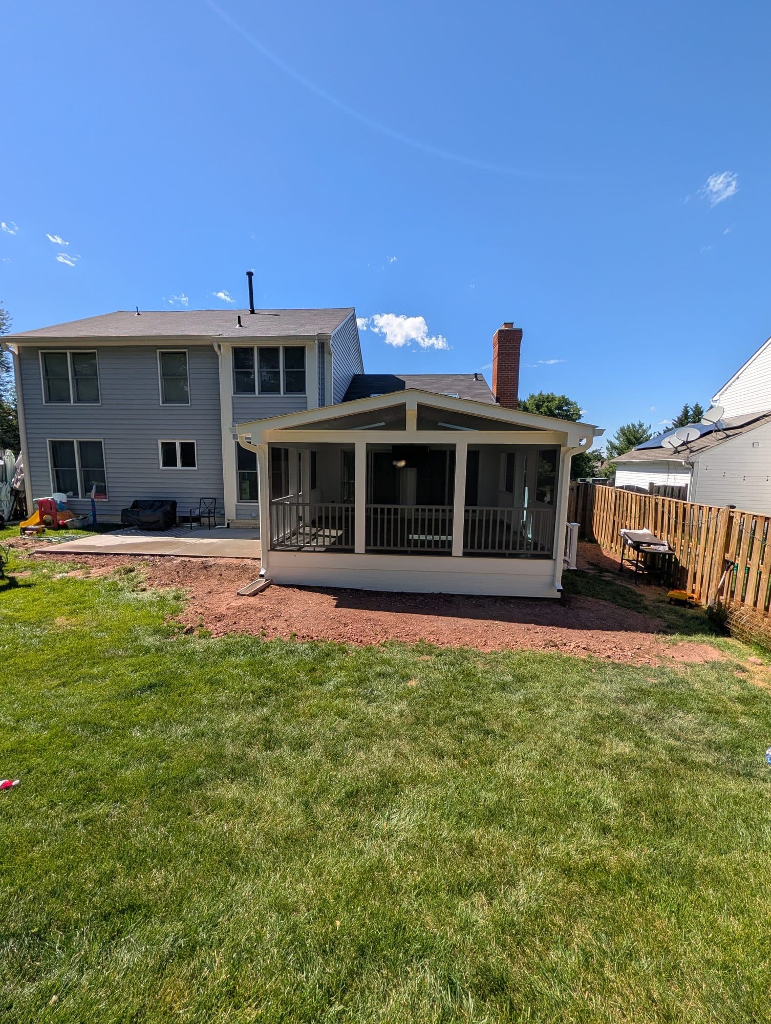 Finished concrete patio in front of a completed screened-in porch addition