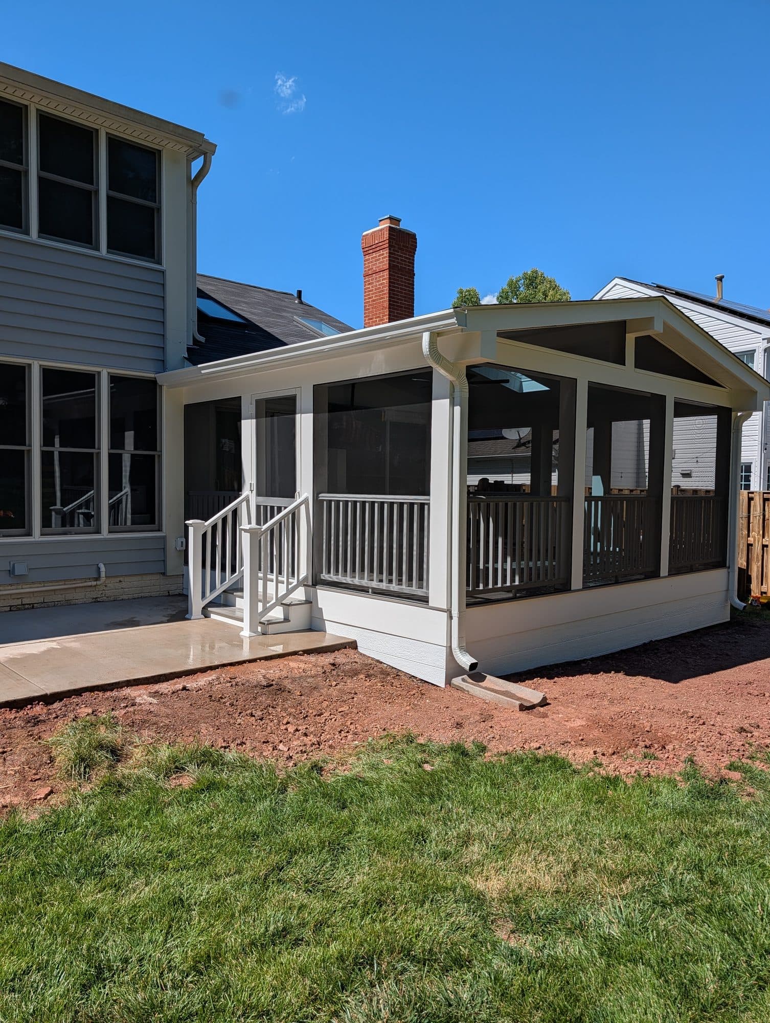Finished concrete patio and steps leading up to a completed screened-in porch addition