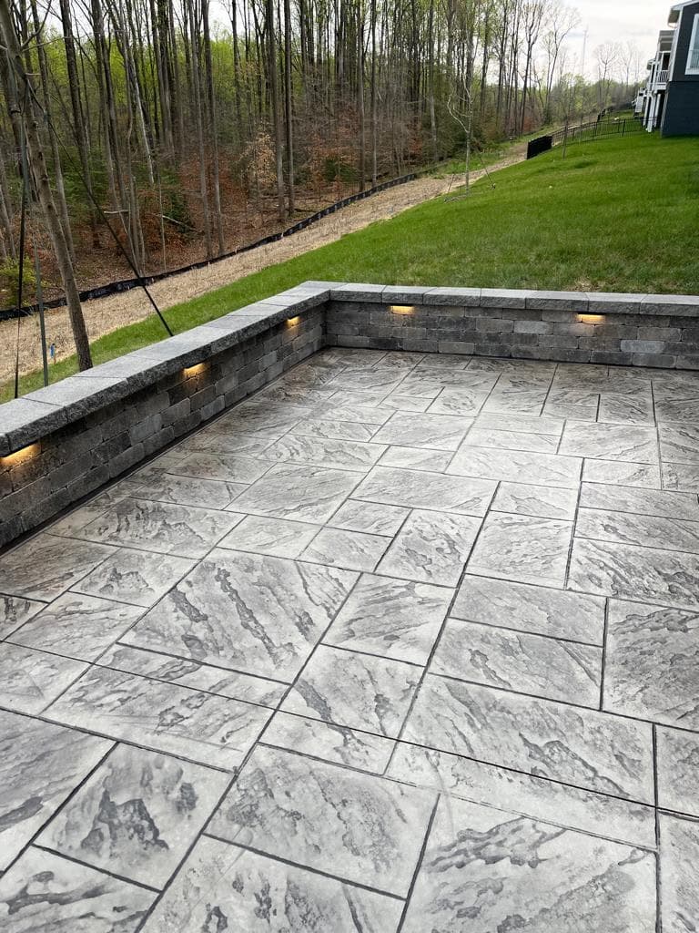 Stamped concrete patio with a curved seat wall and integrated lighting in South Riding