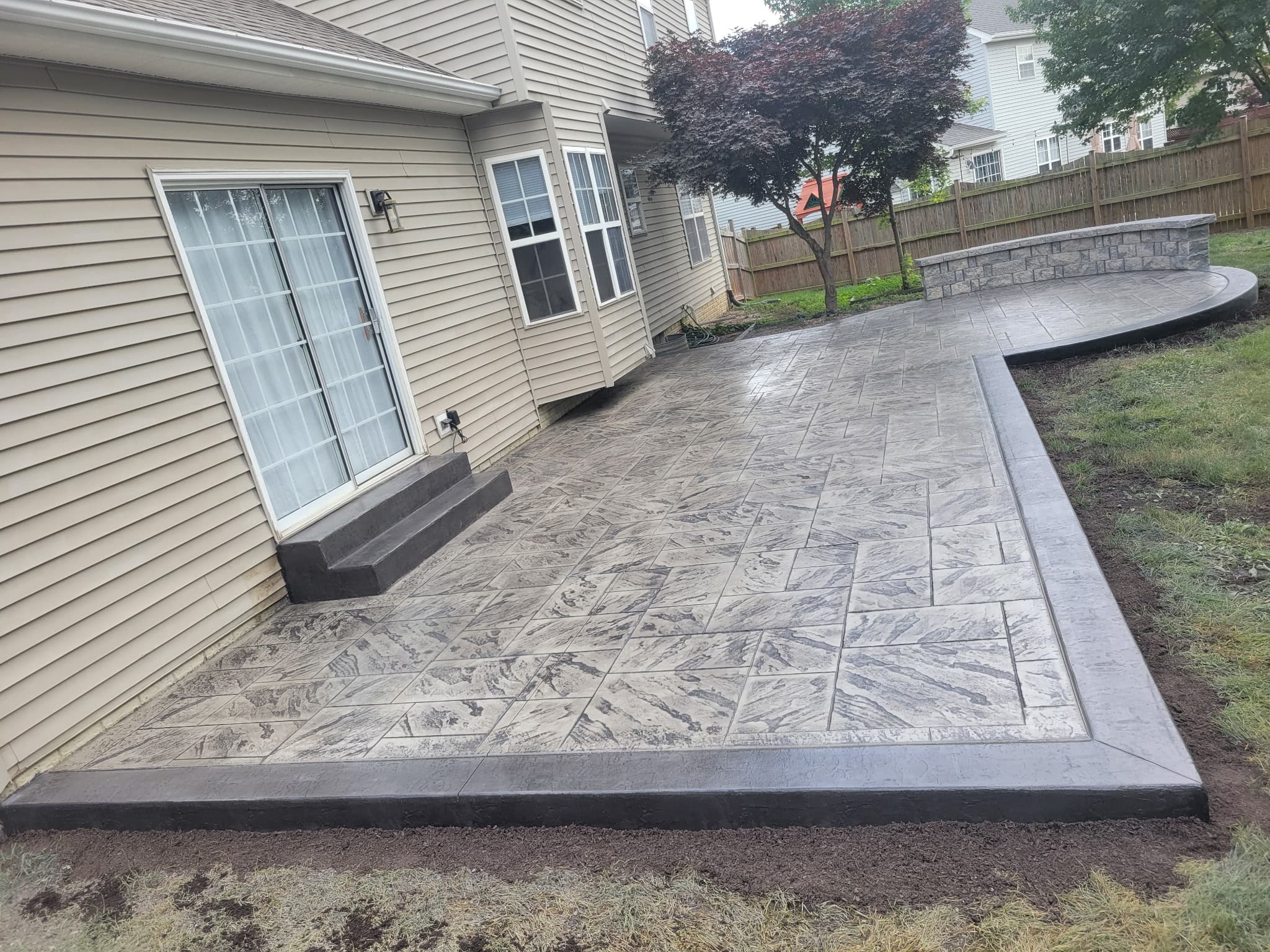 Wide view of a stamped concrete patio and walkway connecting to the back of a home in South Riding