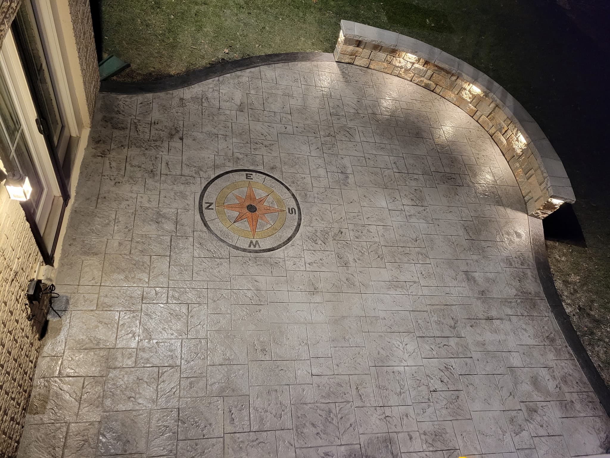 Evening view of the finished stamped concrete courtyard and curved lit stone seat wall in McLean