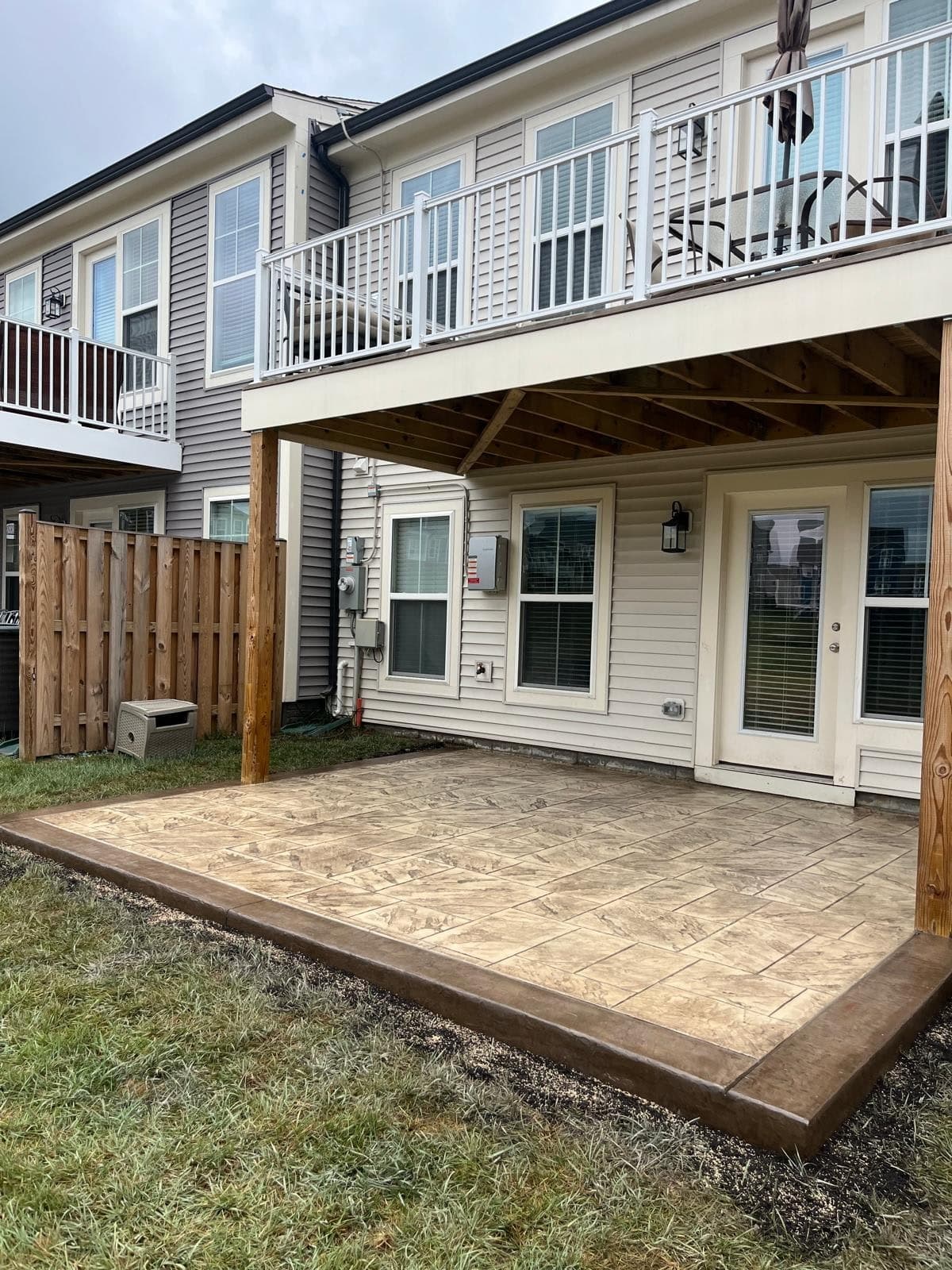 Stamped concrete patio poured under an existing second-story deck in Ashburn