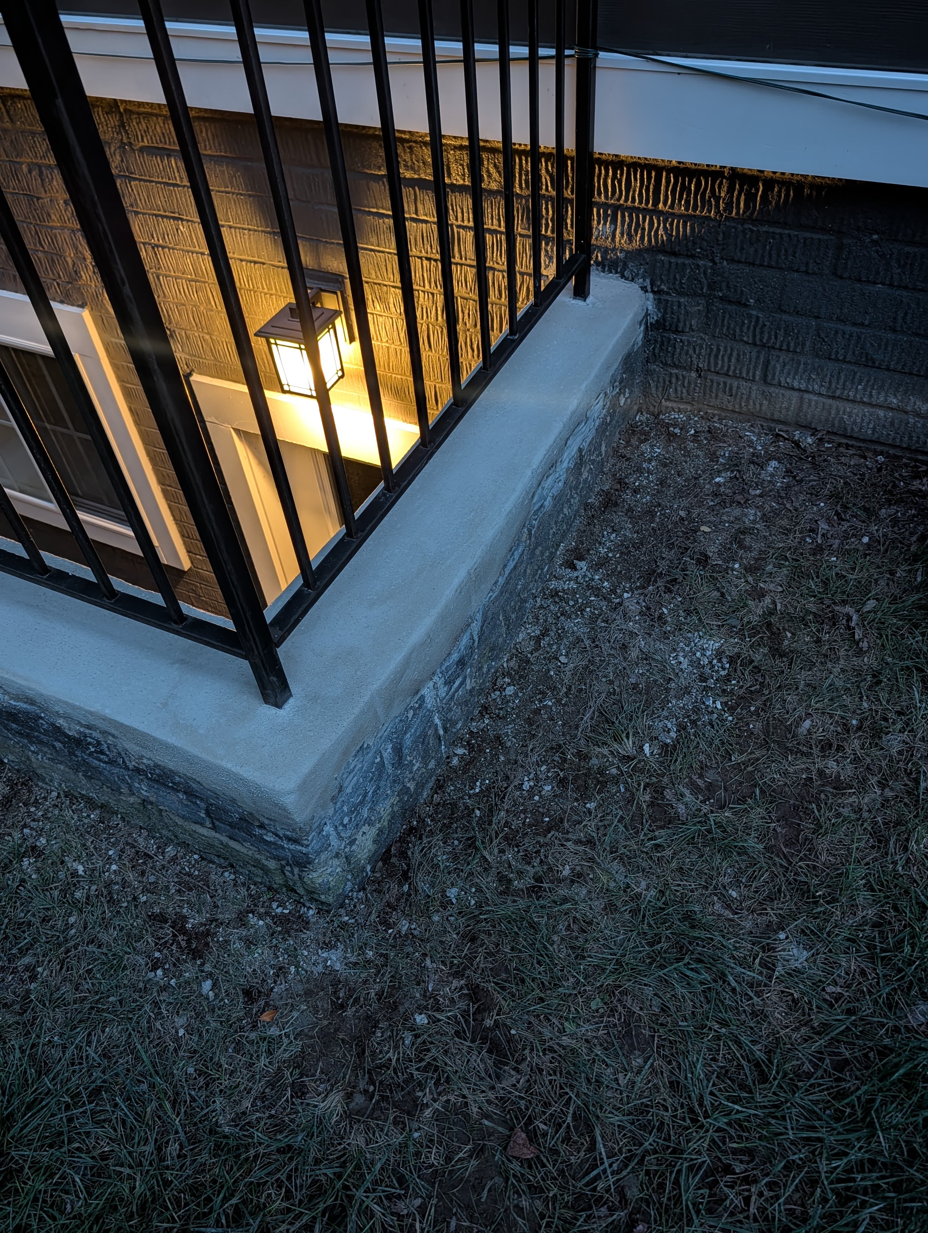 Resurfaced concrete wall cap along the basement stairwell, close-up evening view